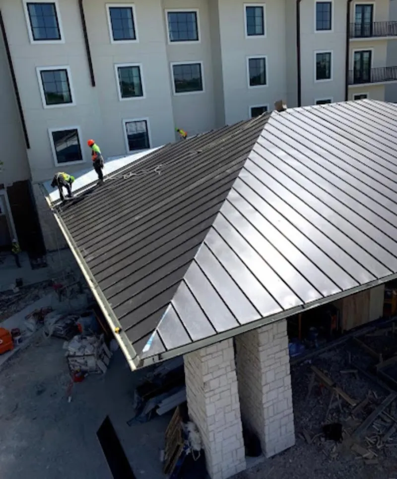 Crew installing standing seam metal roof panels on a commercial project in Portsmouth